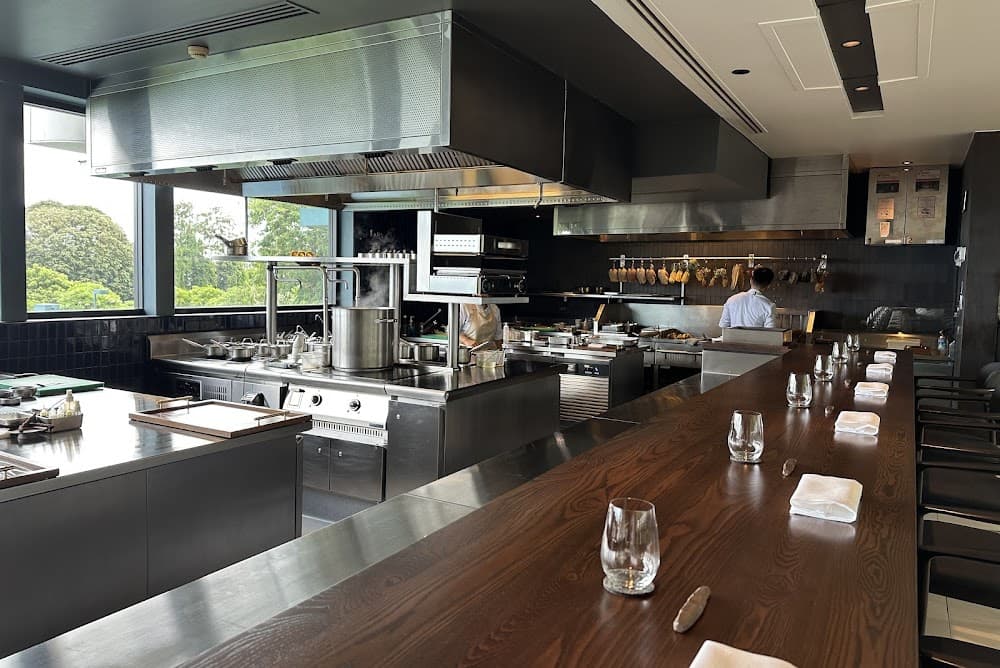 PRU open kitchen counter with dark wood bar seating facing the stainless steel kitchen