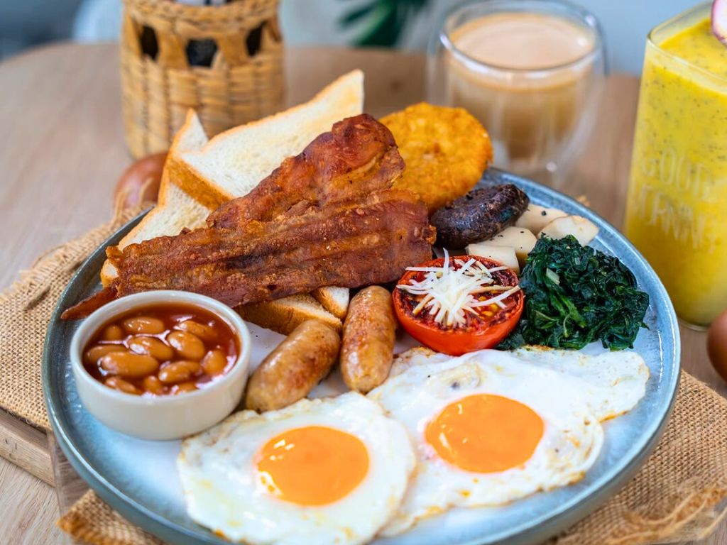 Full English-style breakfast plate with eggs, bacon, toast, sausages, beans, and vegetables at Café Studio in Kata Karon.