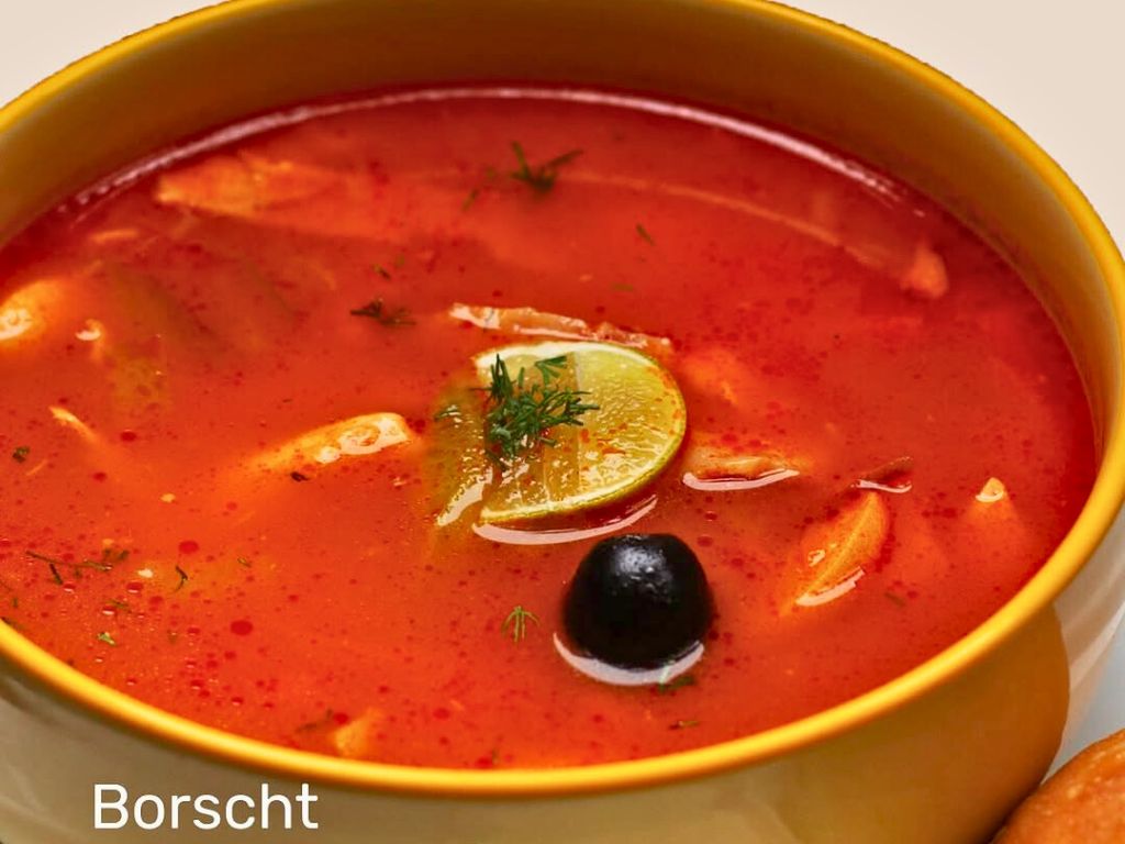 Traditional red borscht soup with lemon, dill, and olive served at Chekhoff Restaurant in Kata Karon, Phuket.