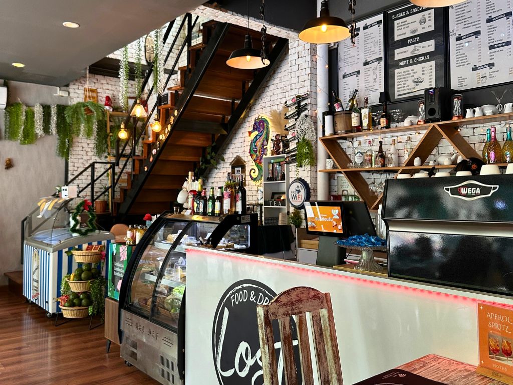 Cosy interior of Lost in Phuket café with modern bar counter, coffee station, hanging lights, and rustic decor in Kata Karon.