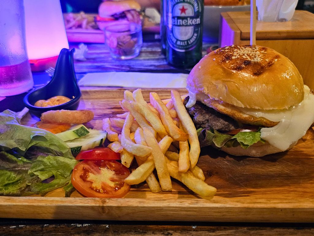 Signature cheeseburger with fries and salad served on a wooden tray at Lost in Phuket restaurant in Kata Karon.