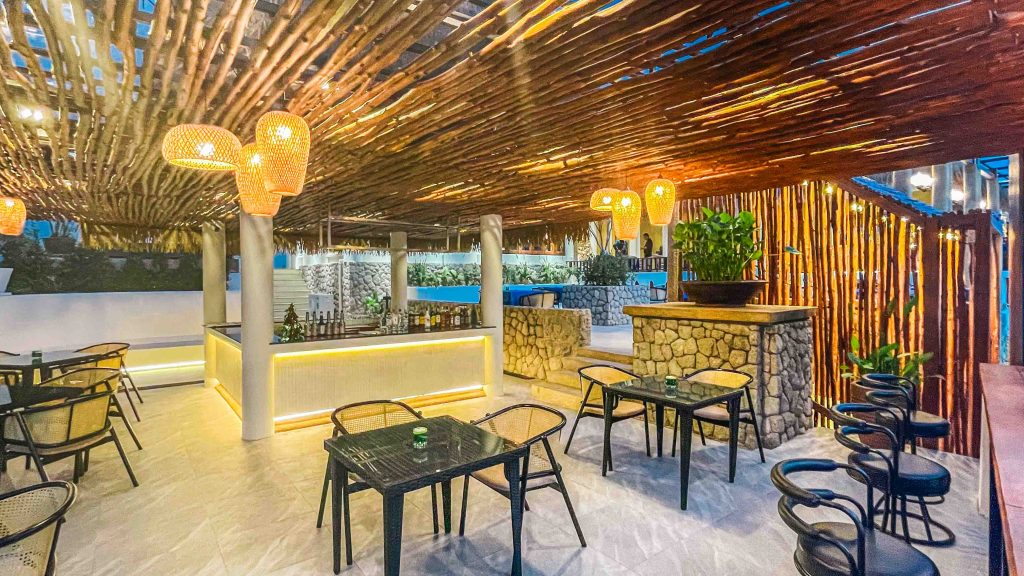 Stylish outdoor seating area at Manow Brunch & Bistro in Kata Karon with rattan lights, stone decor, and a bar counter.