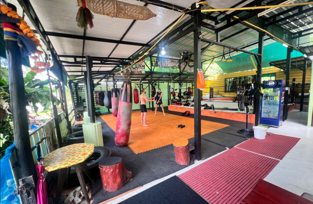 Muay Thai students training at Naka Muay Thai gym in Phuket with punching bags and ring