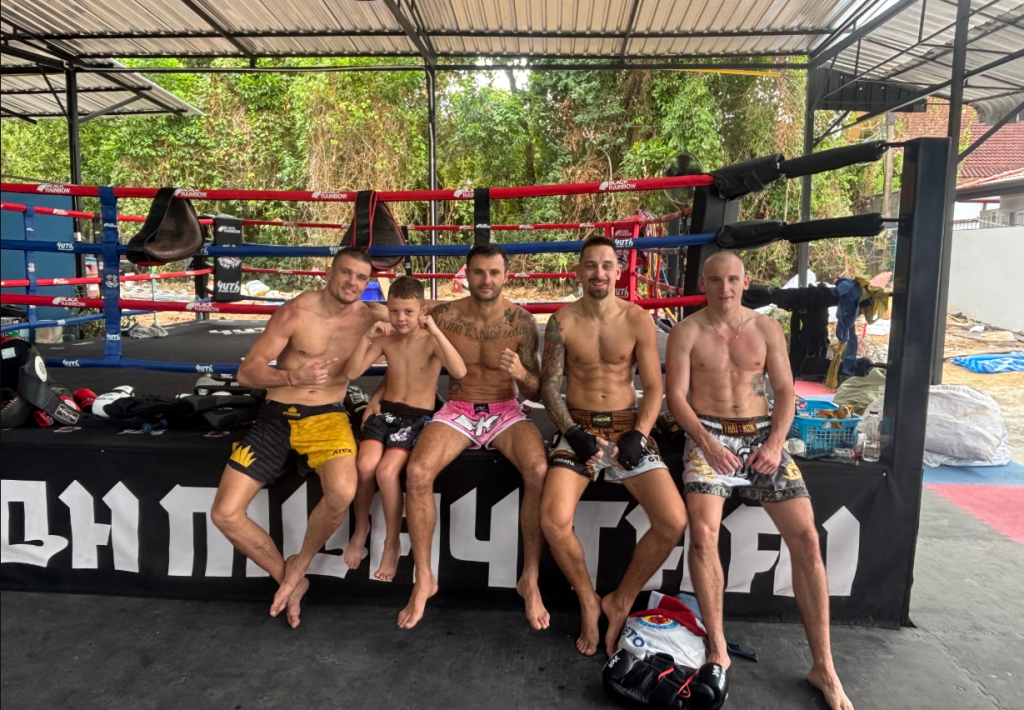 Muay Thai fighters and students at Kru Oh Muay Thai gym in Phuket sitting in front of a boxing ring