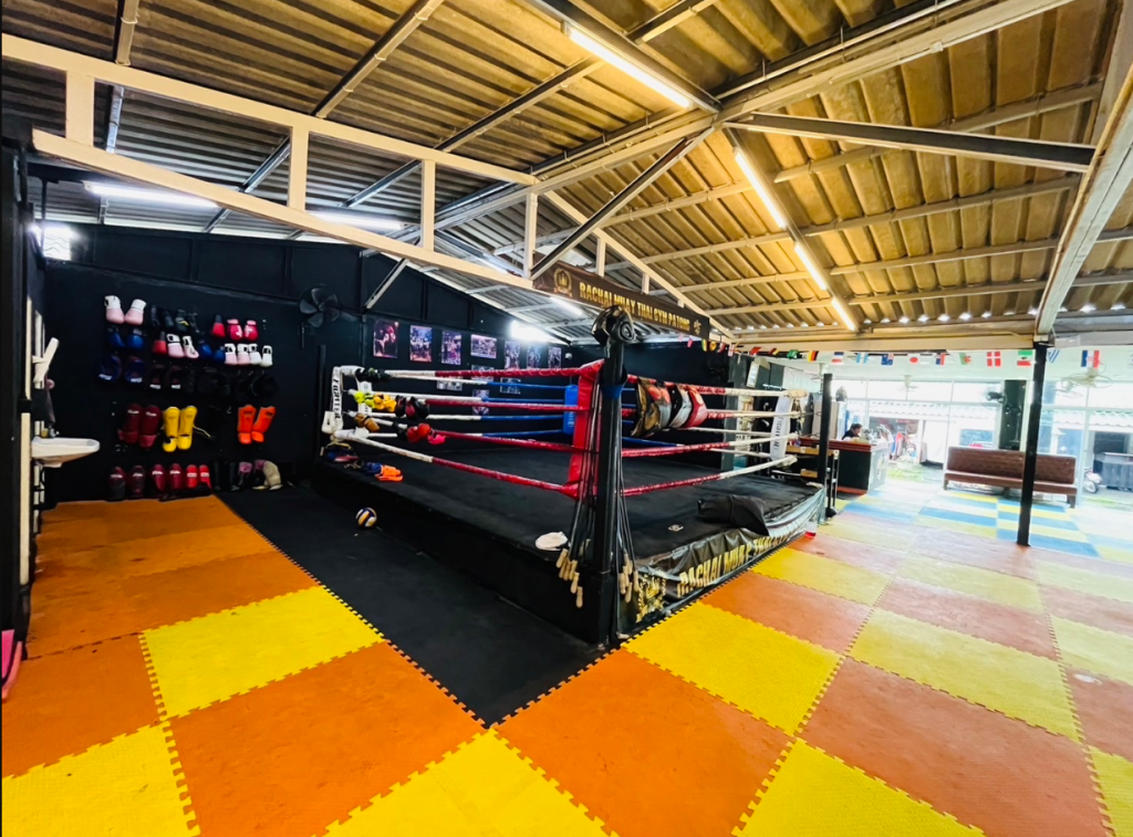 Indoor boxing ring at RC Rachai Muay Thai gym in Phuket with colourful mats and training gloves